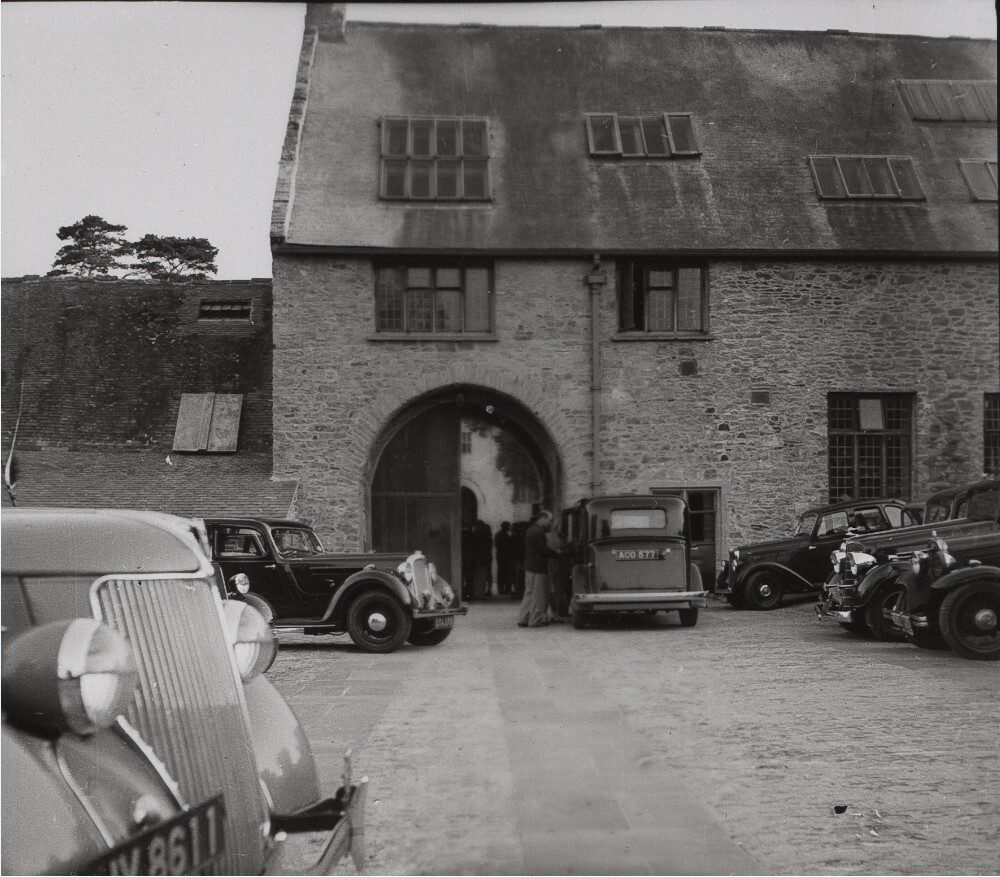 Black and white photo of the entrance to the Barn Theatre, with cars parked outside and people queuing for a performance, c1936